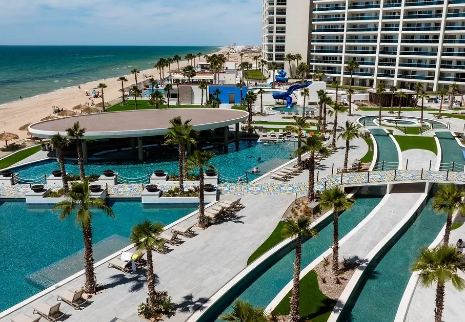 Aerial view of the resort's palm-lined pools, the lazy river, and the beach on the Sea of Cortez